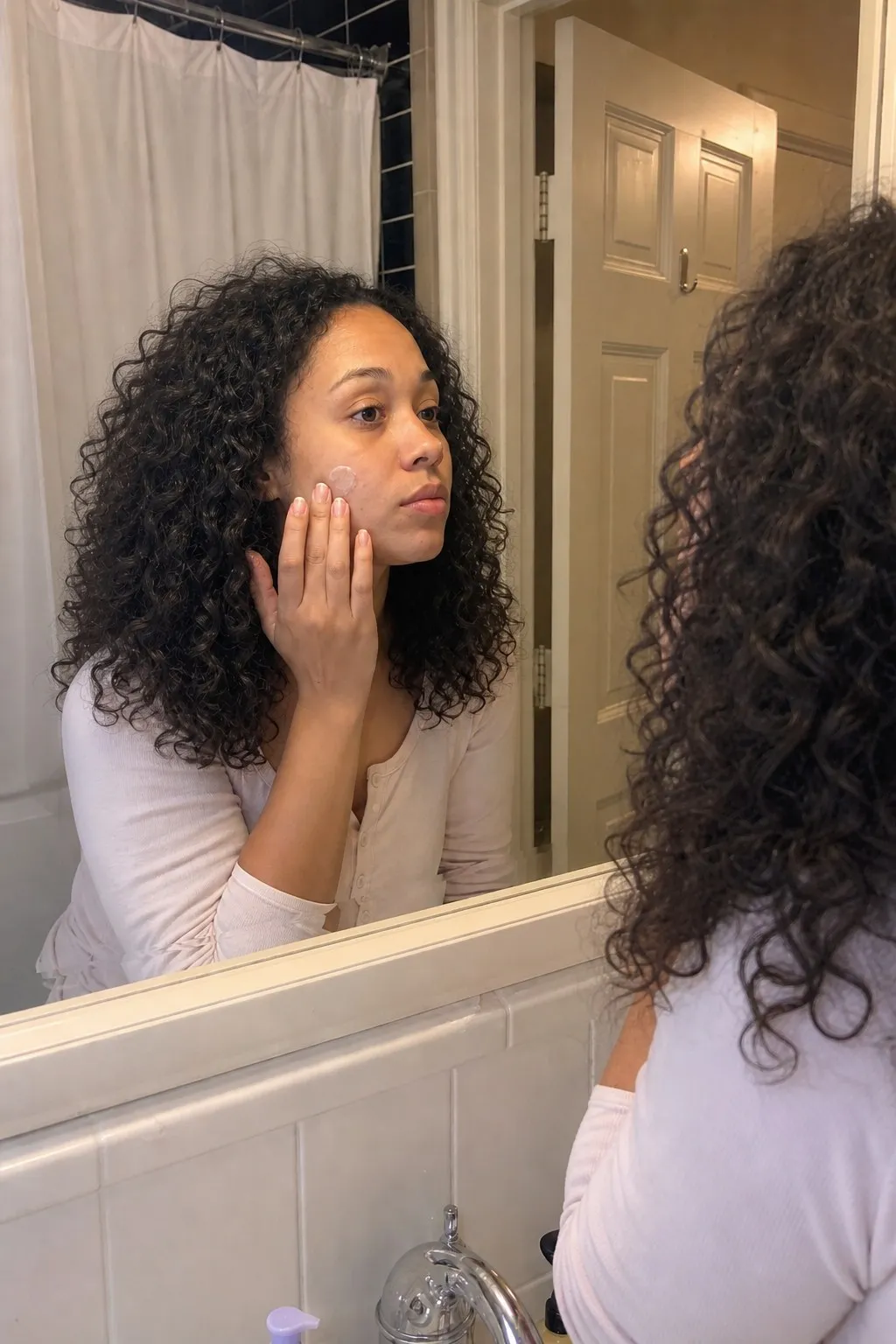 A woman in a bathroom mirror before and after layered curls