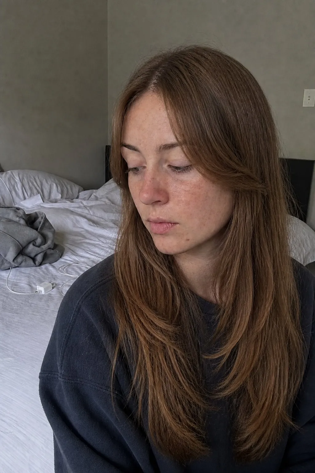 A woman sitting on a bed before and after curtain bangs